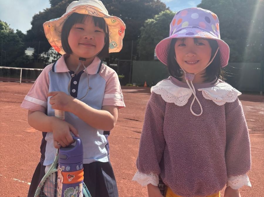 Two young beginner players in sun hats holding racquets at a Temp Tennis beginner class, Vermont South