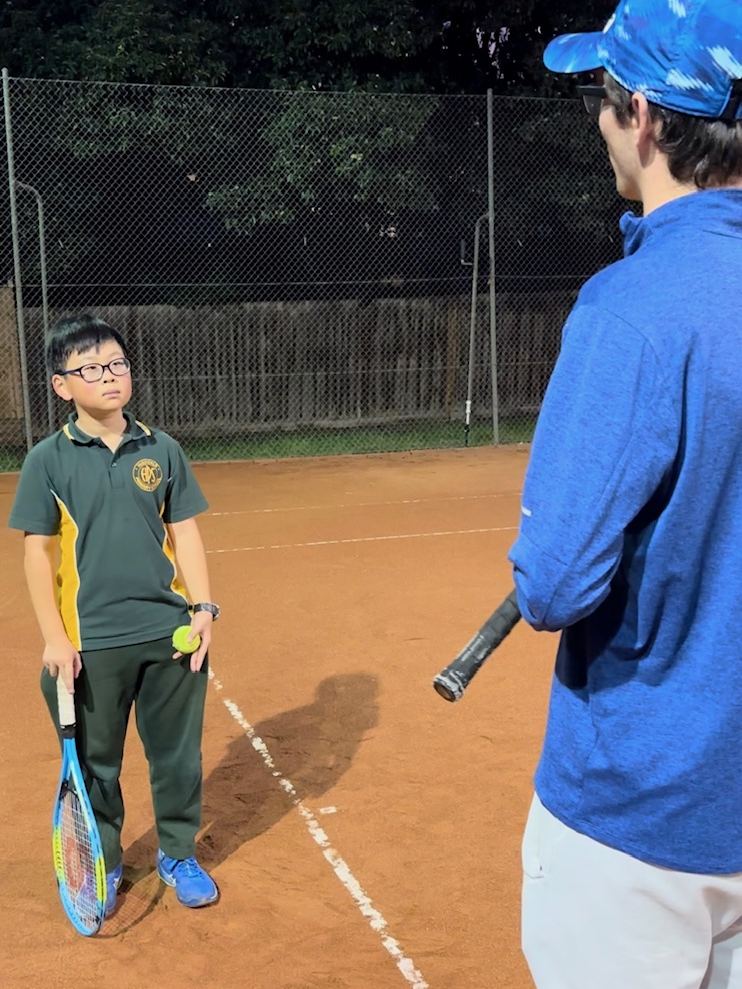 Coach standing with a junior player courtside at Holy Saviour Tennis Club