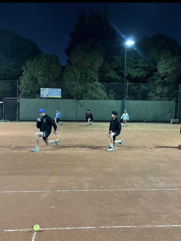 Junior player hitting an overhead serve under lights at Holy Saviour Tennis Club